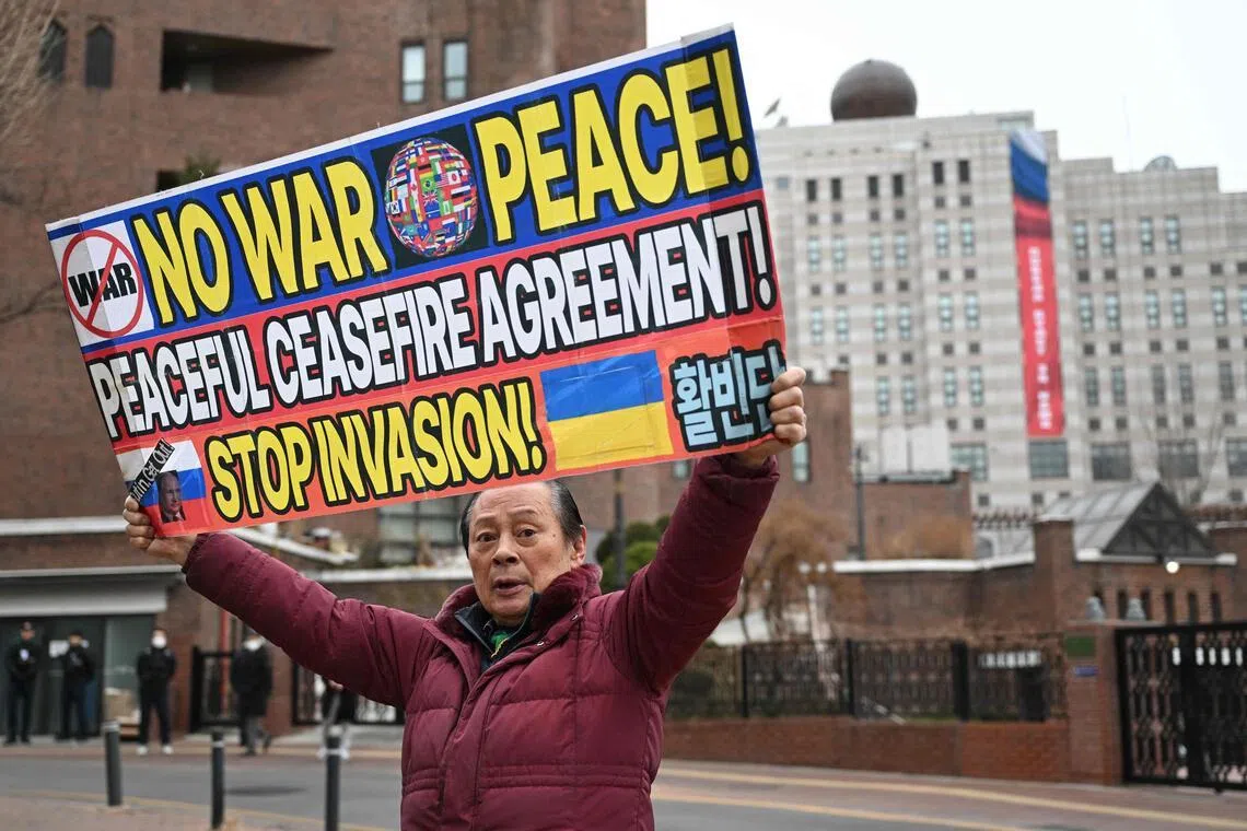 2月24日，一名韩国男子在俄使馆附近高举标语，上面写着“要和平，不要战争”“签署和平停火协议”“停止侵略”。（法新社）