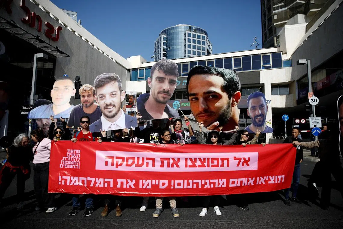 一群以色列民众星期四在特拉维夫高举被扣以色列人质的巨型图像，要求内坦亚胡政府全面执行加沙停火协议，让余下的人质安全重返家园。（路透社）