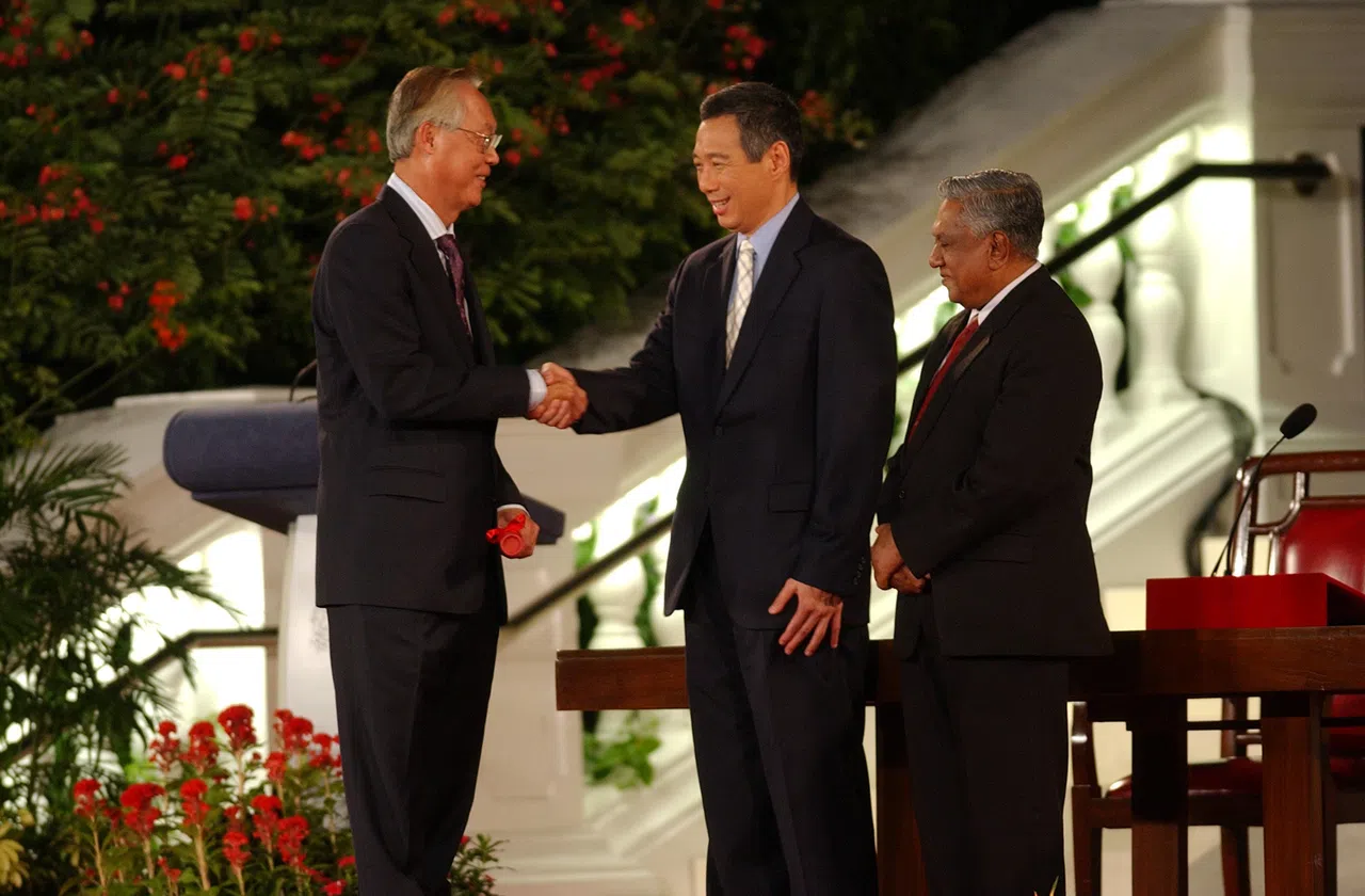 刚宣誓就职的李显龙总理（中）与第二任总理吴作栋（左）握手。右为我国第六任总统纳丹。（档案照片）