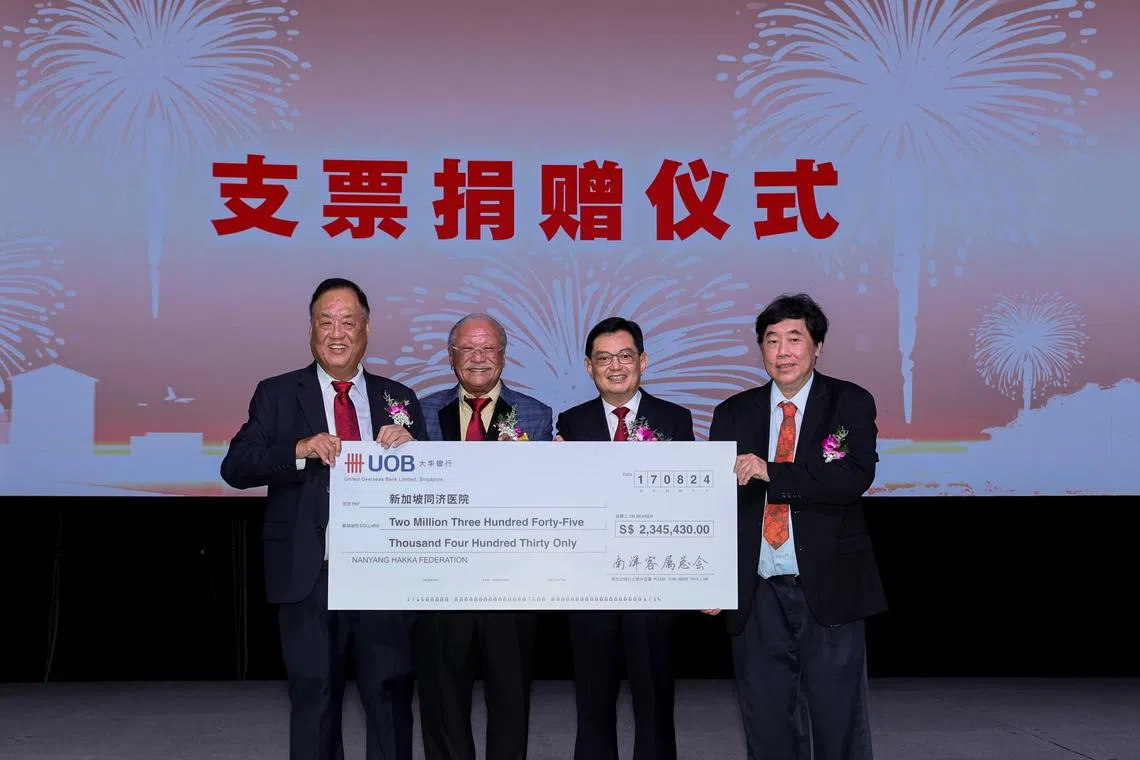 南洋客属总会会长刘智评（左一）在晚宴筹委会主席何谦诚（左二）的陪同下，将客家文化美食节筹得的超过234万元善款，移交给同济医院主席杨应群（右一），由副总理王瑞杰（右二）见证。（龙国雄摄）