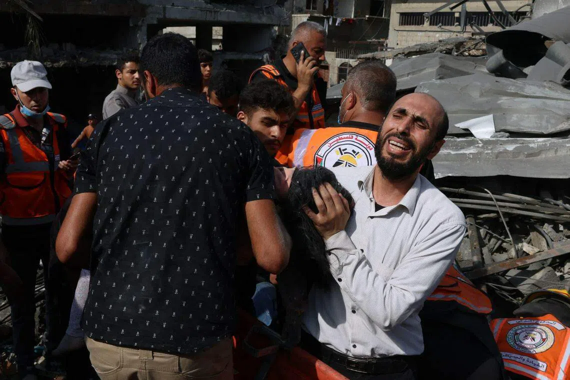 10月22日，以色列炮火再次袭向加沙南部拉法（Rafah），一名父亲在坍塌的废墟中，悲痛地挖出女儿的尸体。（法新社）