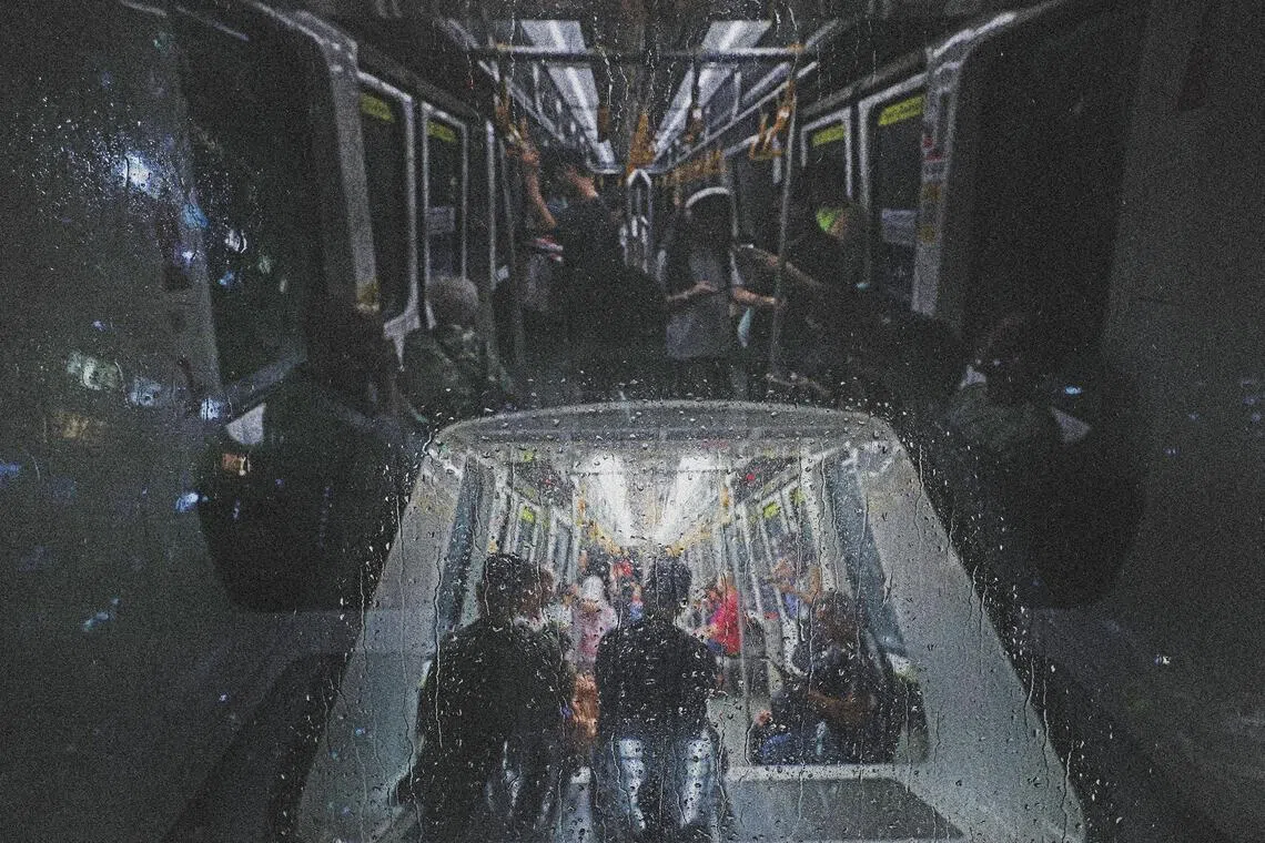 雨滴打在轻轨车窗上，车厢内外景象在玻璃上交错重叠。（陈渊庄摄）