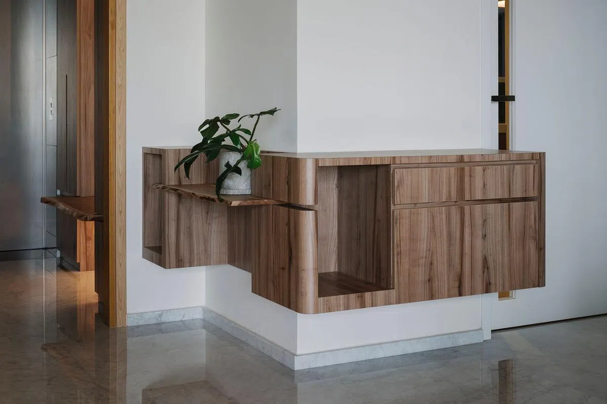 玄关墙的悬浮壁橱做L形设计，有暗示空间方向感作用——直走进入客饭厅，左转下廊道进入卧室。设计师留下屋主旧橱的木板，插入壁橱变成置物台面。（Metre Architects提供照片）