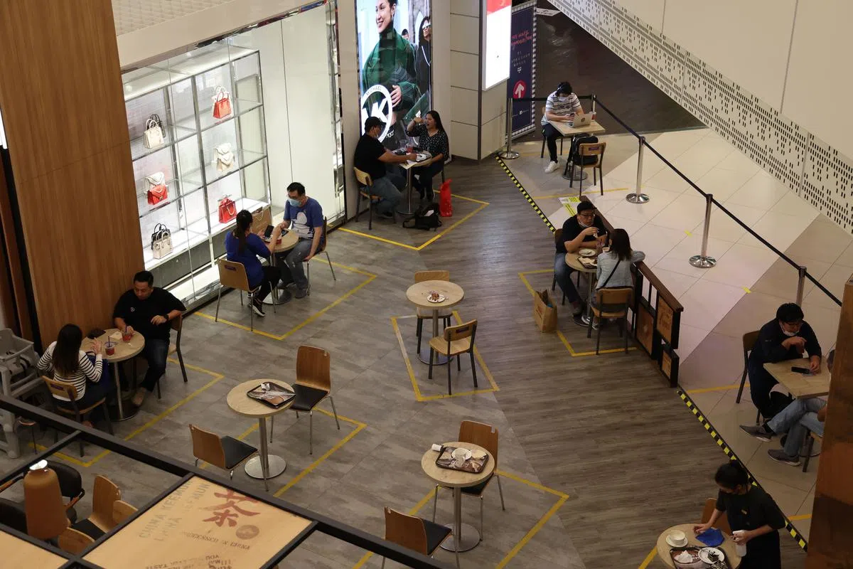 社区病例激增，我国开始收紧堂食人数，一桌只限两人。商场餐饮店重新调整桌椅，为每组食客“划清界限”。（陈斌勤摄）