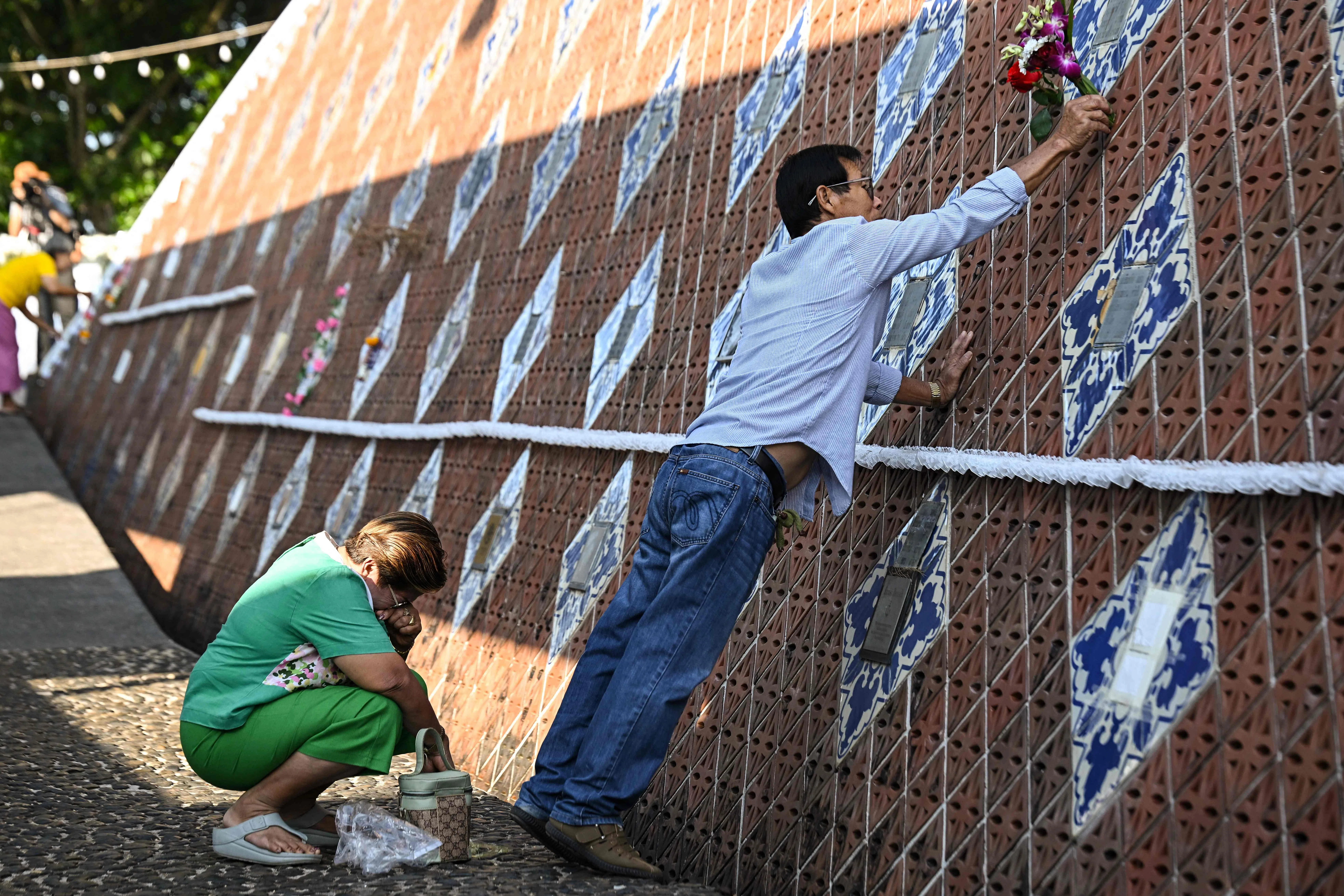 遇难者家属在泰国南部攀牙府的海啸纪念墙上为亲人献花。（法新社）