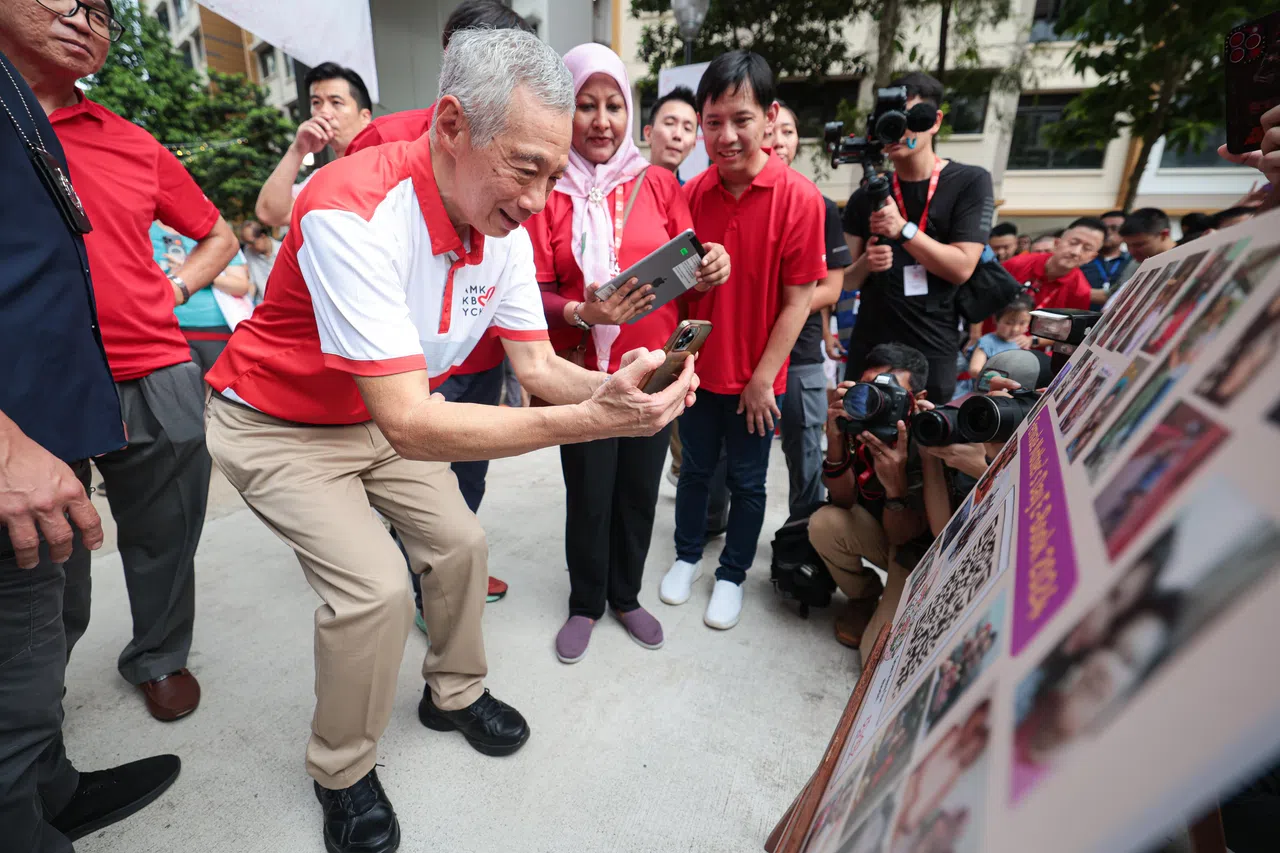 李总理扫描QR码，阅览参赛的芬维尔区居民与各自母亲之间的温馨故事。（李冠卫摄）