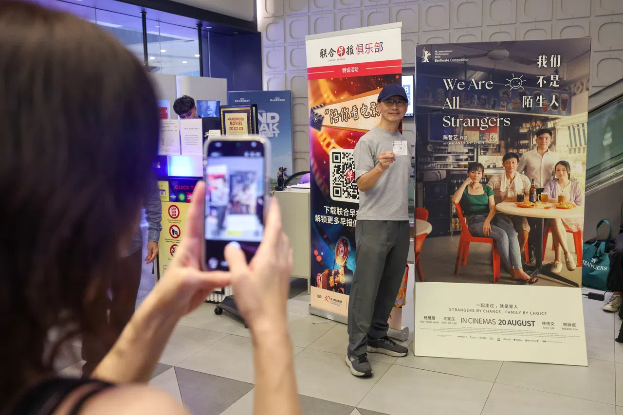 早报俱乐部VIP会员在《我们不是陌生人》海报前拍照留念。（陈渊庄摄）