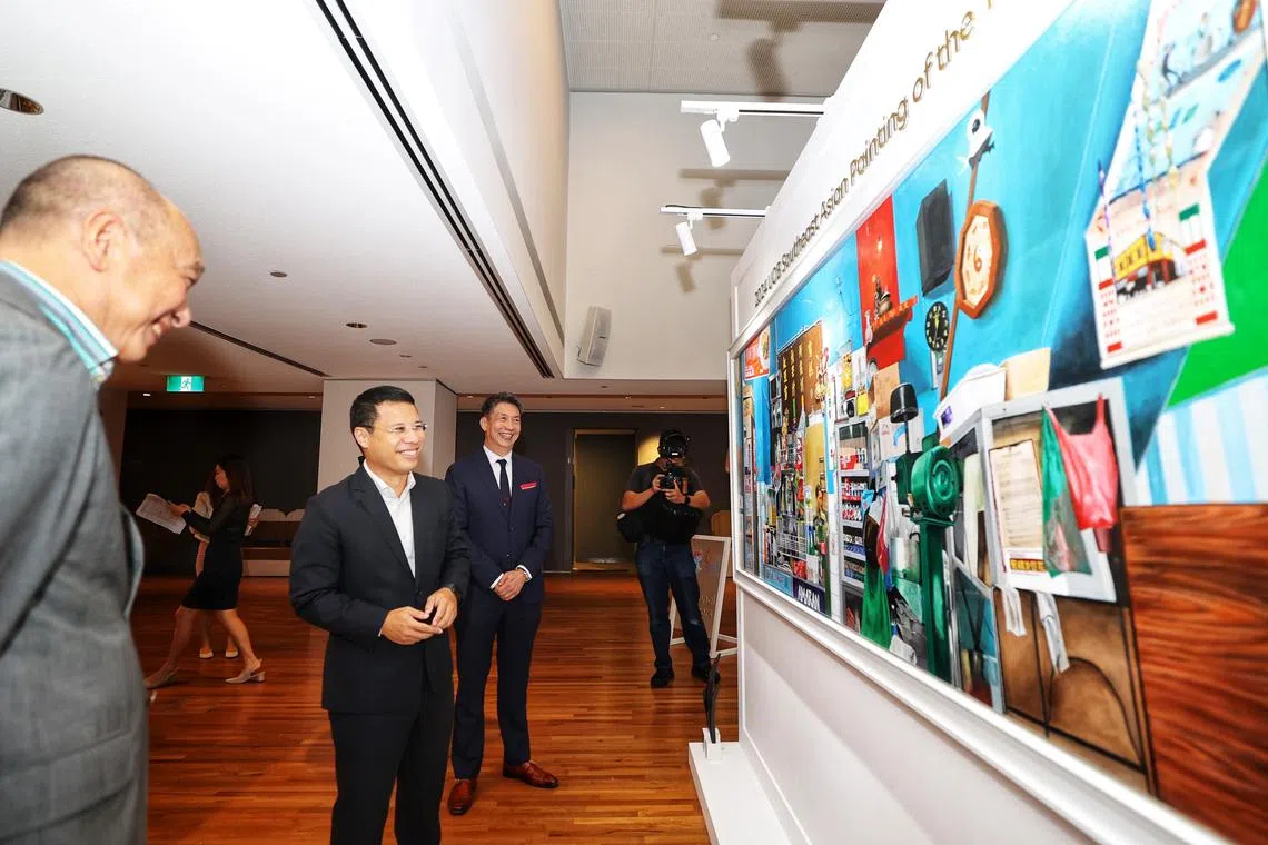 国家发展部长李智陞（左二）和大华银行副主席兼总裁黄一宗（左一）观赏大华银行绘画比赛双大奖得主杨伟伦（左三）的得奖作品《品味时光》。（萧紫薇摄）