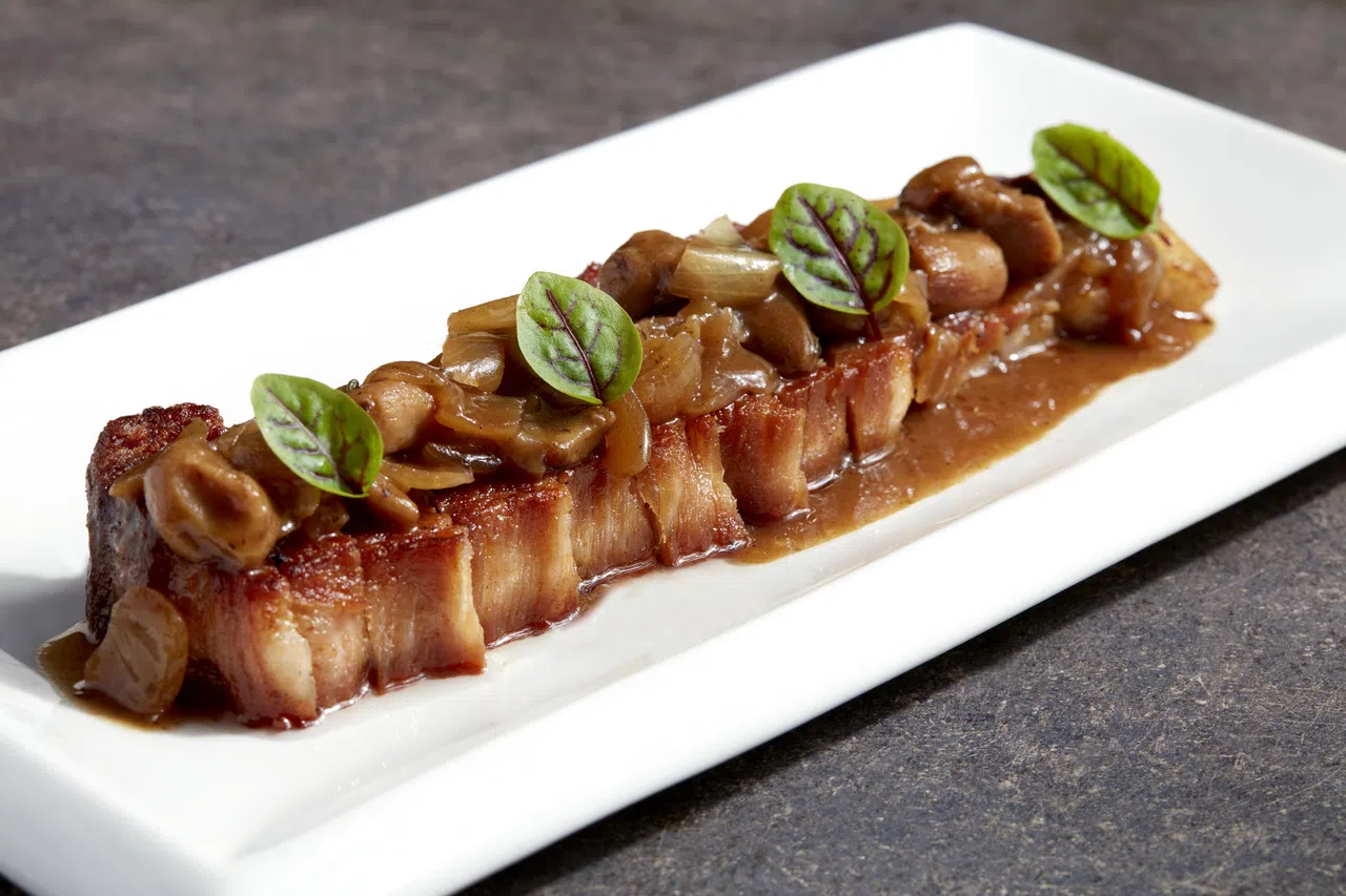 伊比利亚脆皮三层肉表皮酥脆，内里多汁，搭配牛肝菌碎与猪肉汁调制的酱料享用。（餐馆提供）