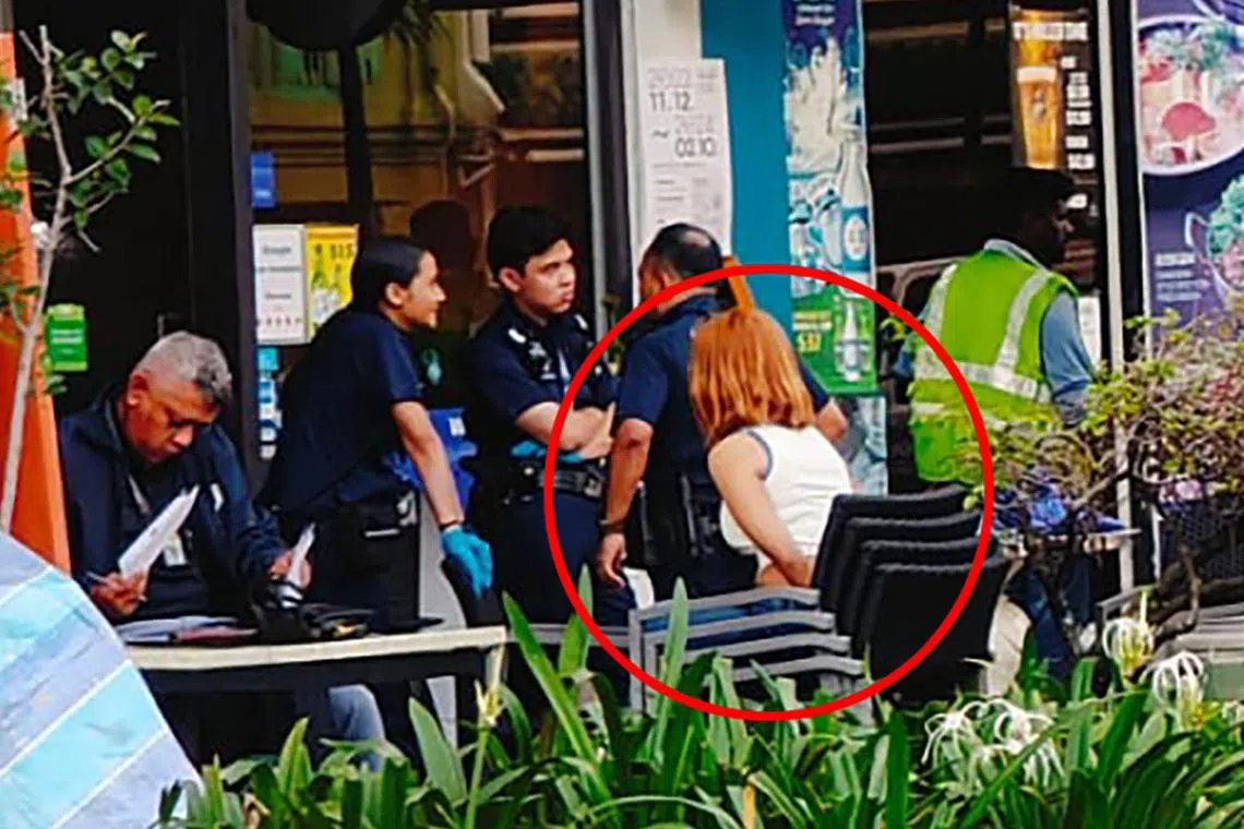 根据读者提供照片，一名金发女子双手绕向后方疑是被上铐和接受警方盘问。（受访者提供）