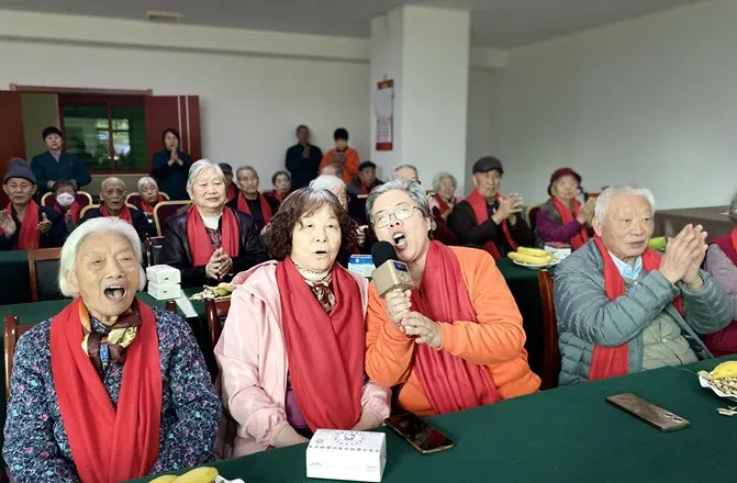 来自洛阳97岁的樊晓雯老人和74岁的陈杏芝老人拿着话筒，带领长者高声吟唱《欢乐中国年》。 （洛阳群安医养院提供）