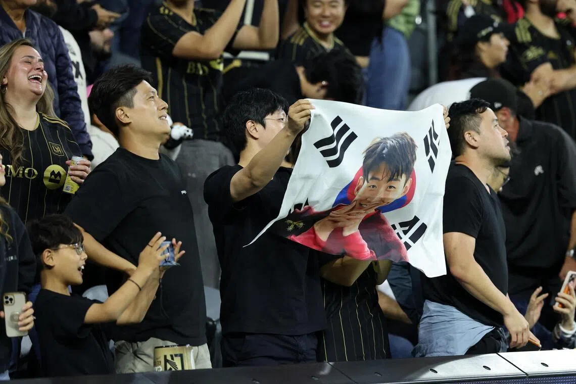 孙兴慜如今成为洛杉矶庞大韩裔社群的精神象征。图为当地球迷拿着印有他的头像的韩国国旗前往现场观赛。（路透社）