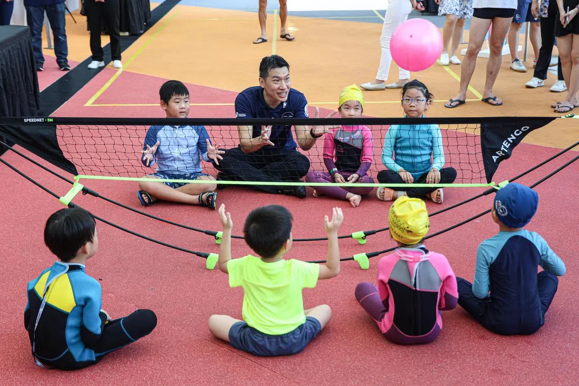 代部长梁振伟（面对镜头者，左二）在为活动主持开幕后，在游泳中心内与公众互动，也与在场的儿童玩游戏。（关俊威摄）