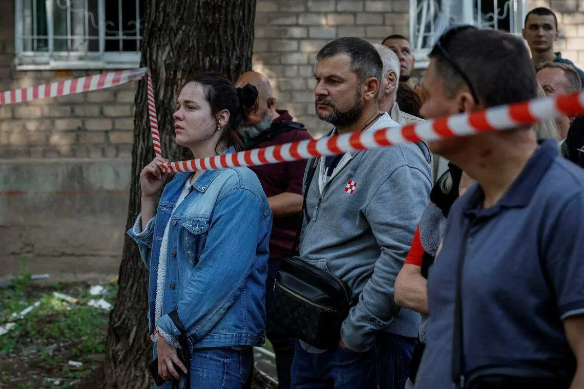 幸存的住户站在警戒线外看着已成废墟的家园。（路透社）