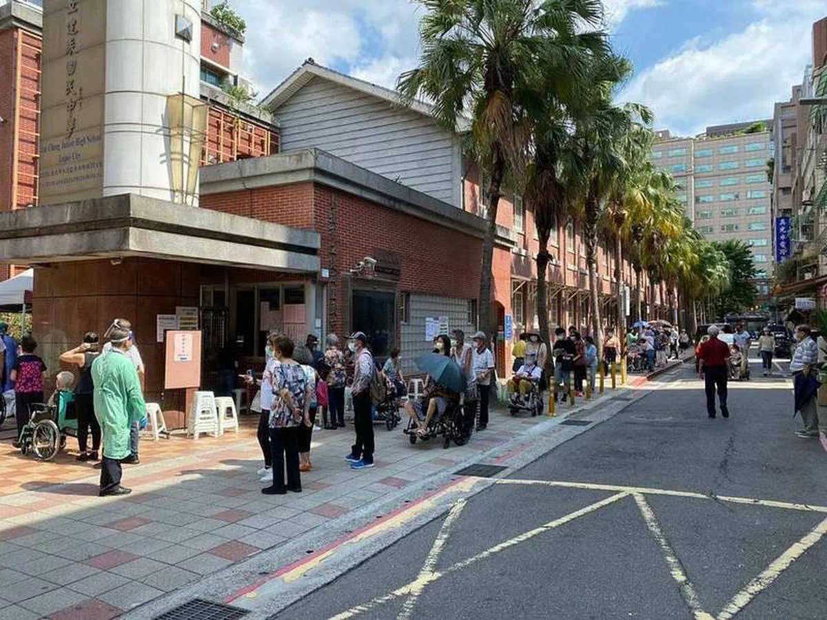 民进党台北市议员梁文杰昨天在社交媒体贴出照片说，台北市府没明确告知施打时段，让许多长者挤在施打点外排队晒太阳。（梁文杰面簿）