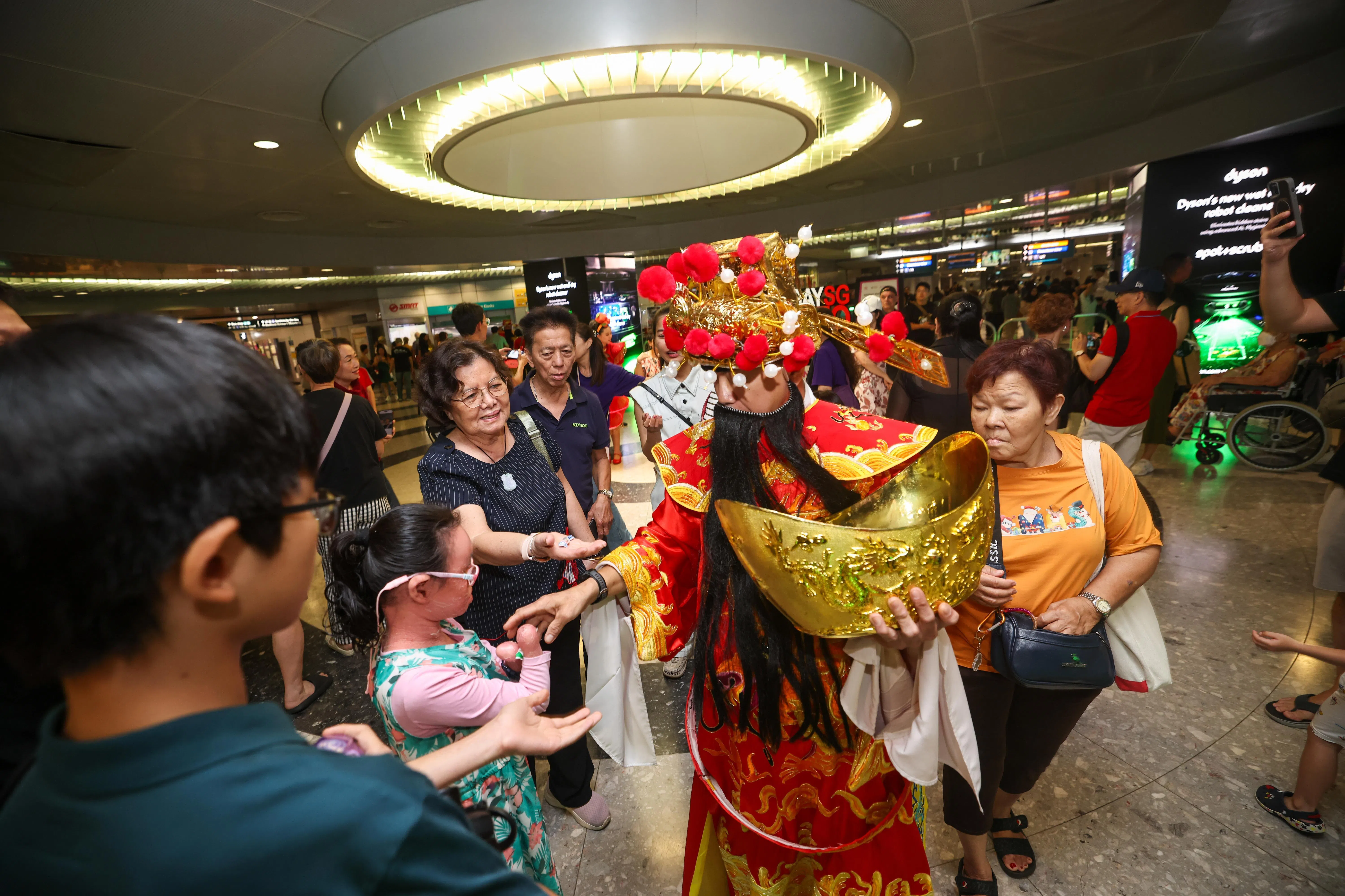 72岁的陈瑞花（右一，背包者）喜爱“妆艺走一走”中的马来族演出者，也对财神饶有兴趣。（陈渊庄摄）