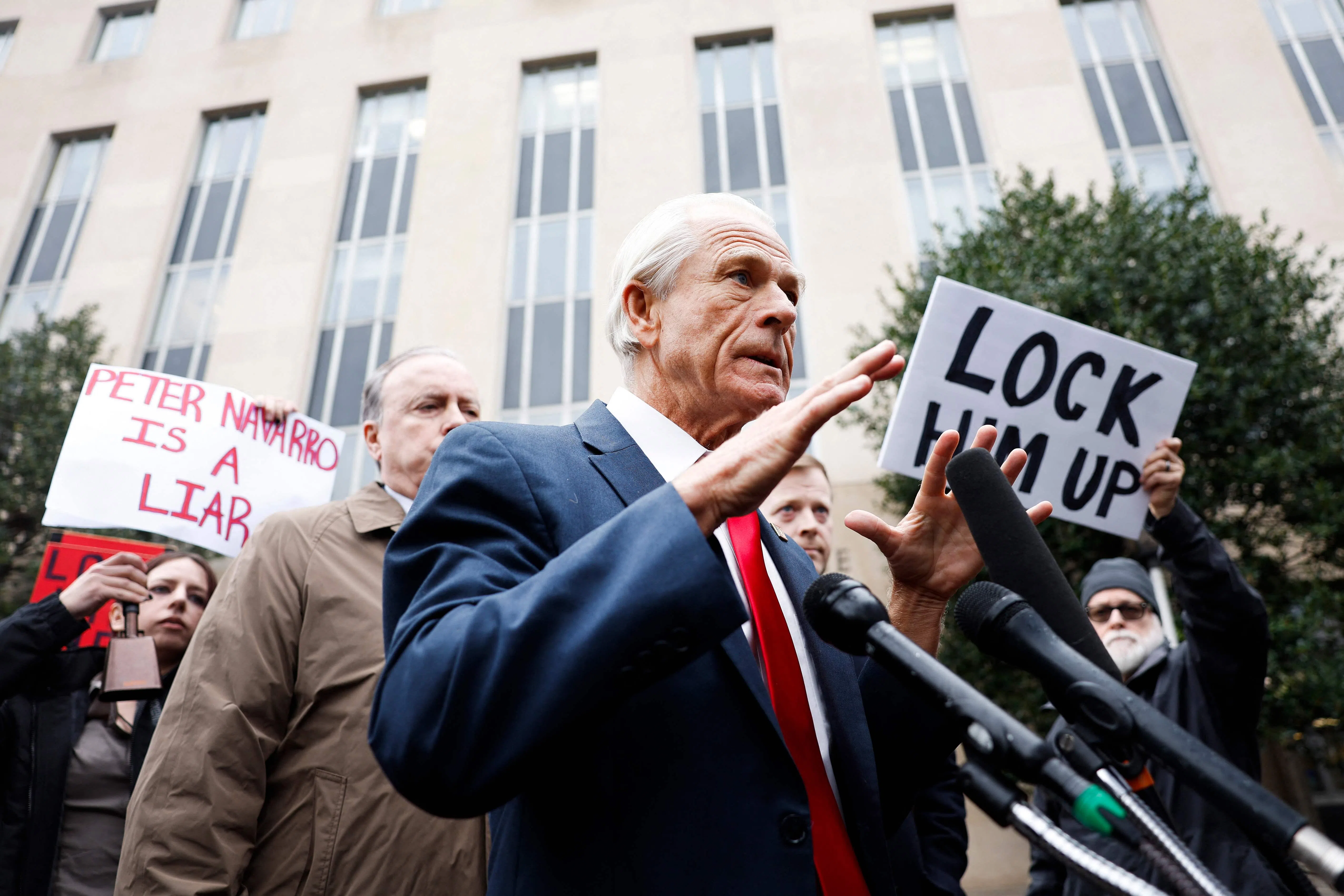纳瓦罗在法院外向媒体讲话时，一些民众在他身边高举“把他关起来”“纳瓦罗撒谎”的字牌。（法新社）