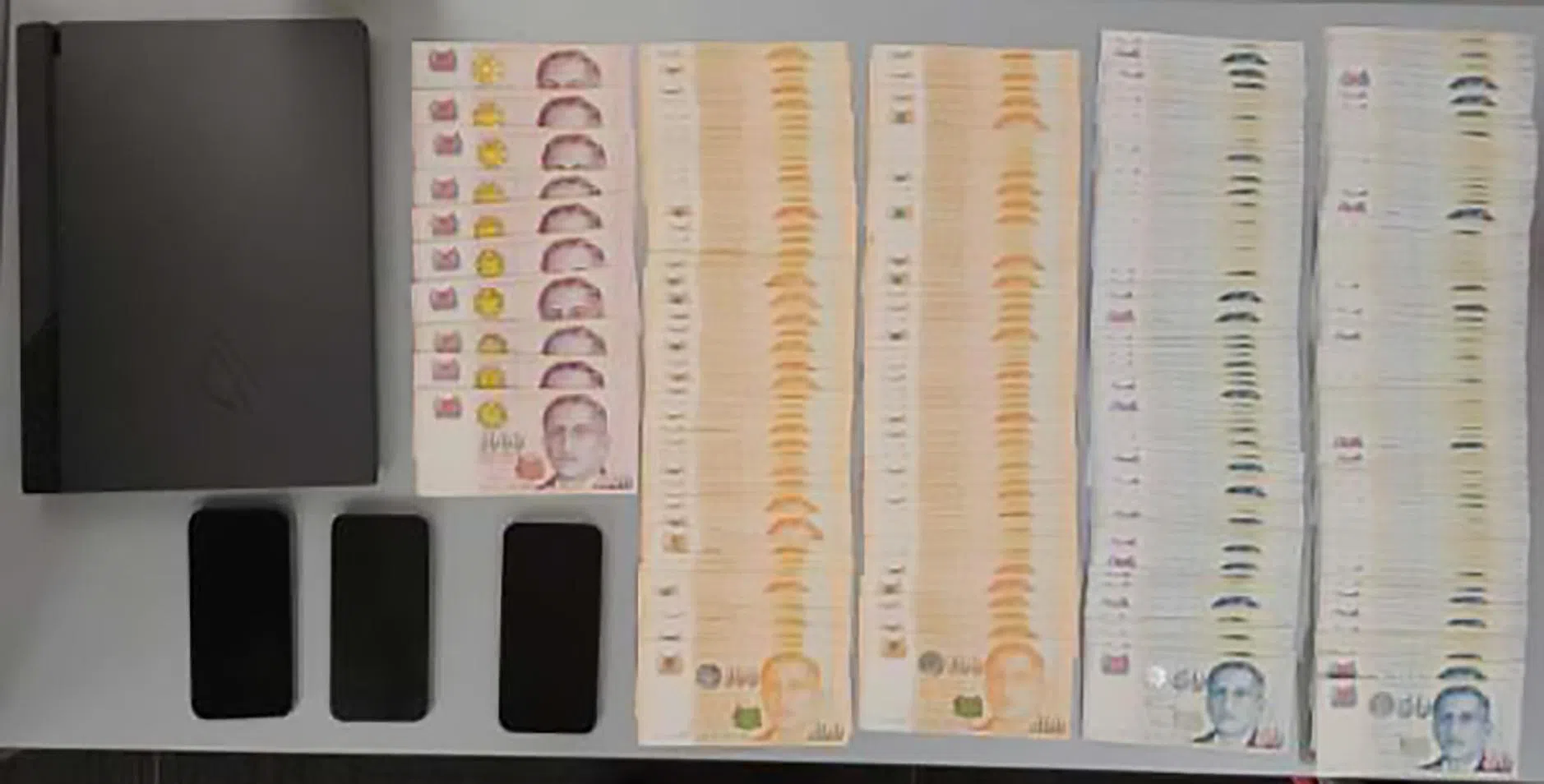 除了电脑和手机等电子器材，当局也起获大量现金。（新加坡警察部队提供）