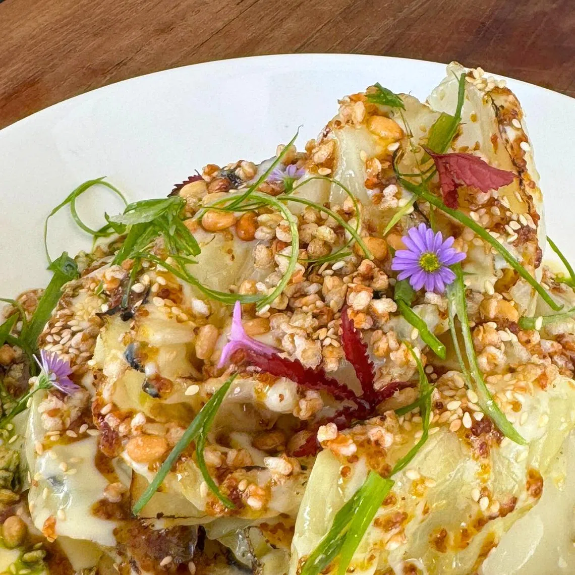 烤包菜撒满荞麦脆粒、香烤松子和白芝麻。（餐馆提供）