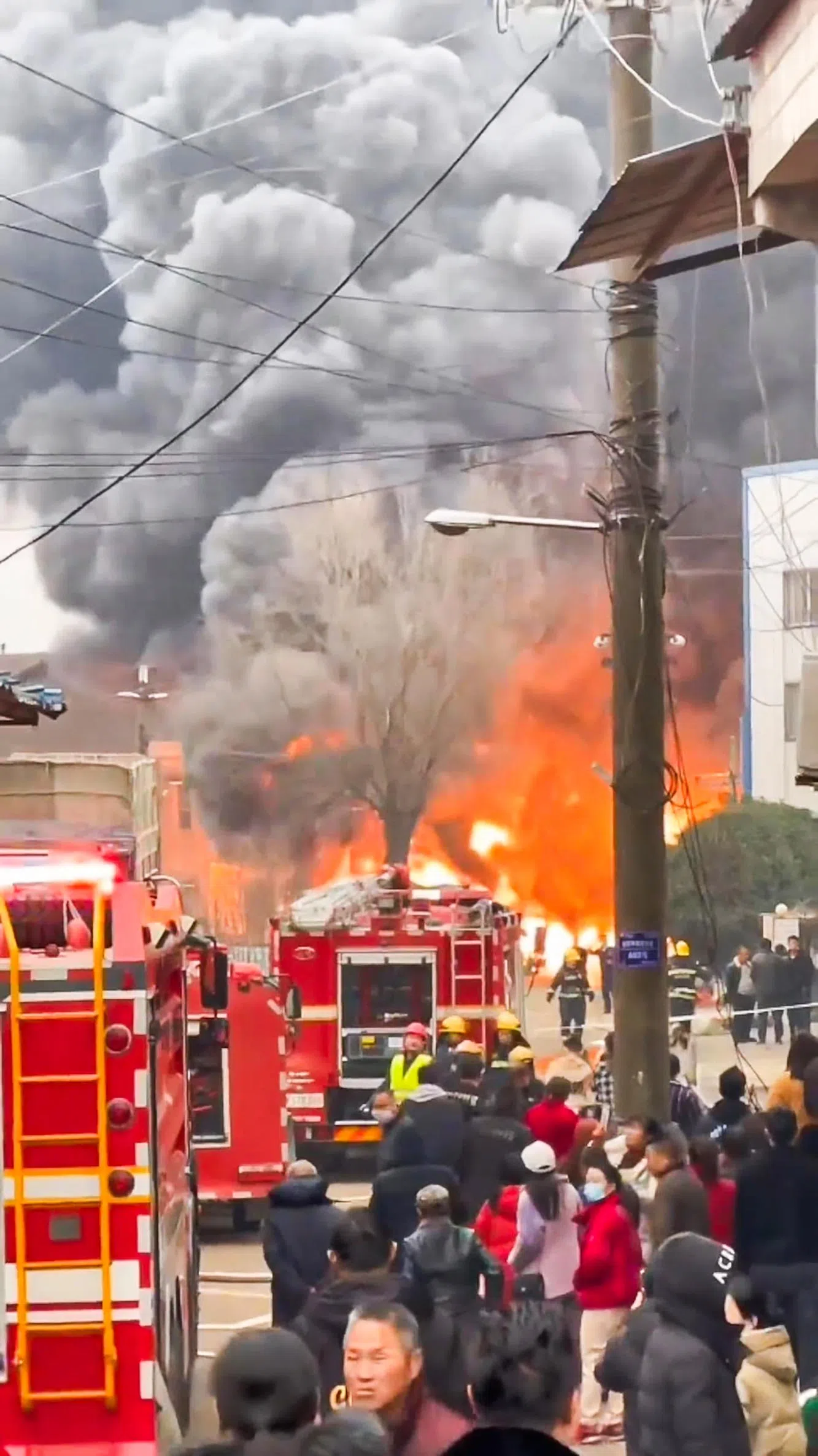 网络流传视频显示，火灾发生时，现场黑烟滚滚，不断向上蔓延，火势极为凶猛。起火饭店前面的马路，已停有多辆消防车及围观的路人。（互联网）