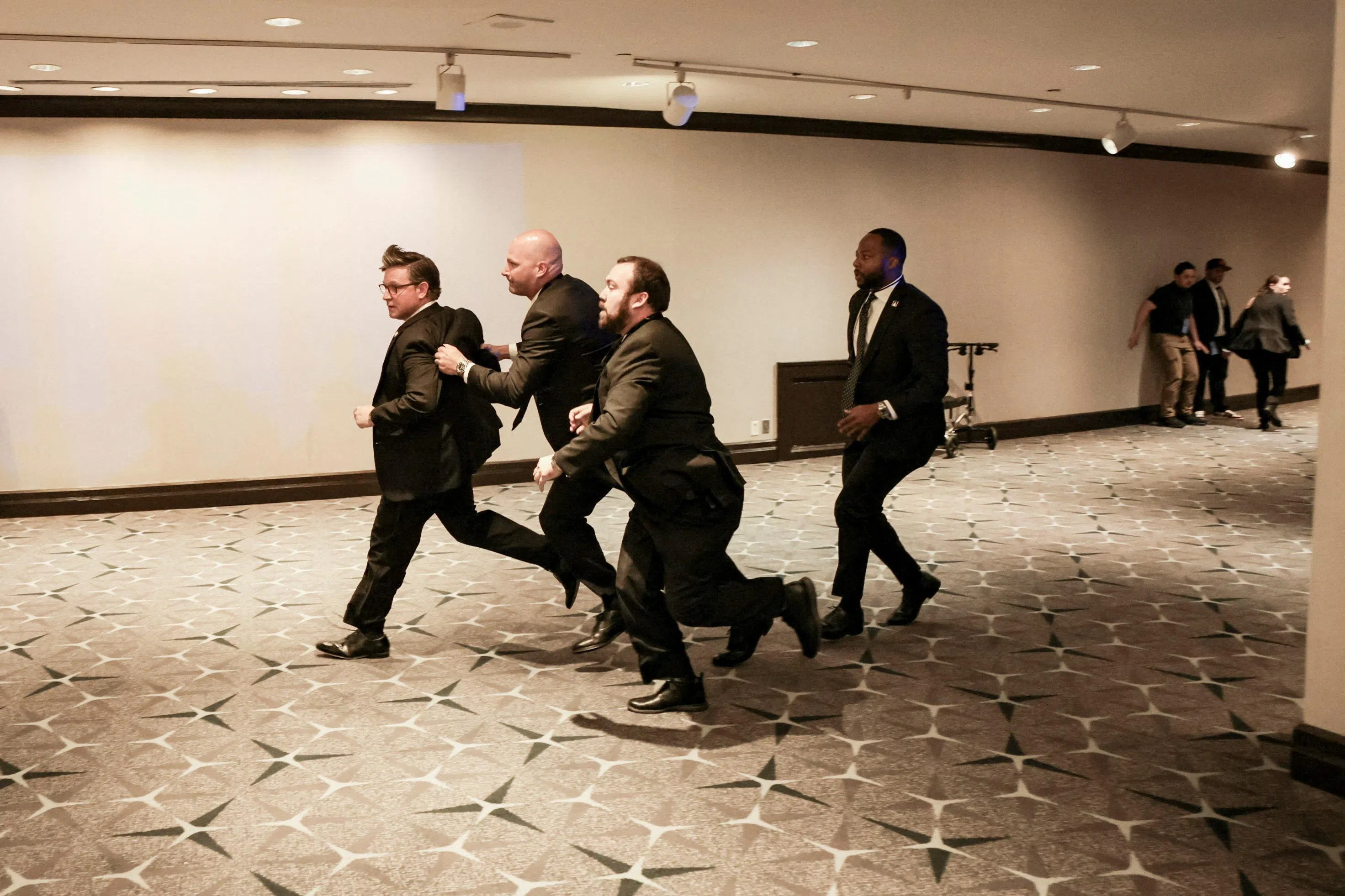 白宫记者晚宴发生枪击事件后，美国众议院议长约翰逊（左一）由安保人员护送离场。（路透社）