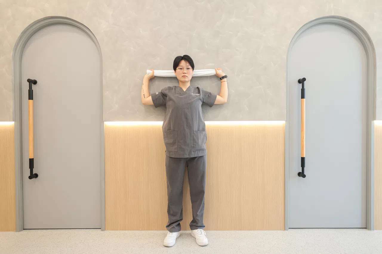 肘部微微弯曲，缓慢拉下毛巾，靠近后颈，胸部打开，感受背部肌肉收缩。（李冠卫摄）