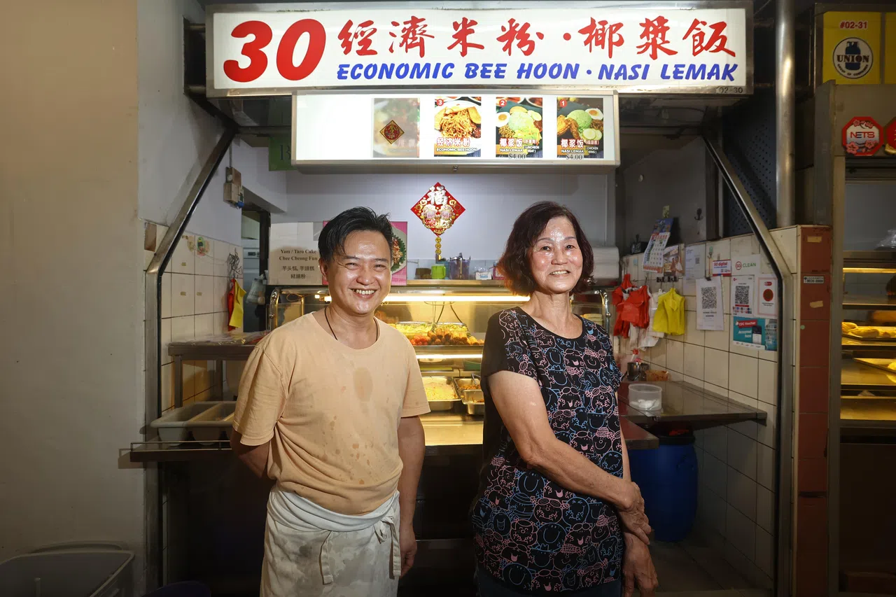 潘雅强（左）与李柳春（右）两人因为摊位转让而相识，李柳春向潘雅强传授了烹煮椰浆饭与炒米粉的技巧，以及经营摊位的秘诀。（陈渊庄摄）