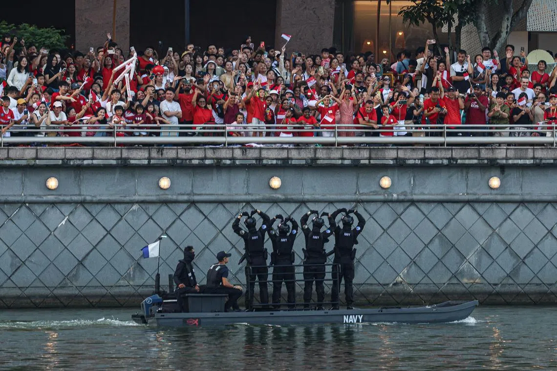蛙人跳伞后，乘坐快艇向滨海湾周围的公众打招呼。（关俊威摄）