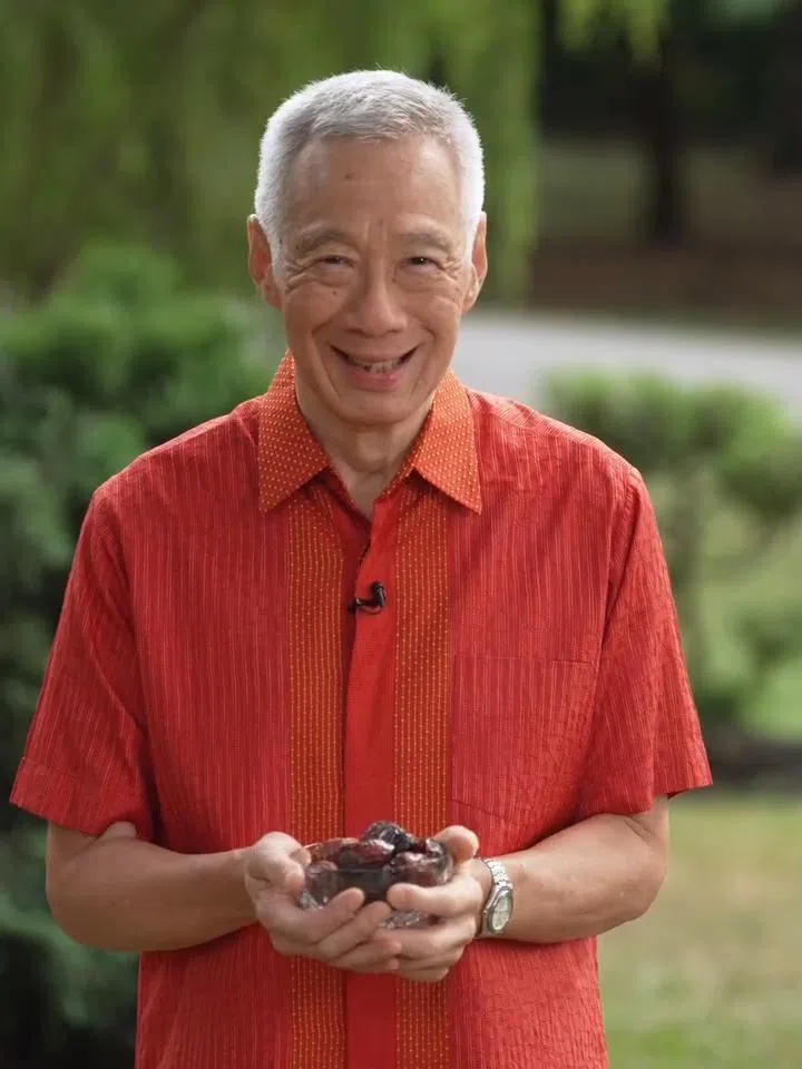 国务资政李显龙捧着回教徒开斋时吃的椰枣，用马来语祝回教徒斋戒快乐。（资政脸书视频截图）
