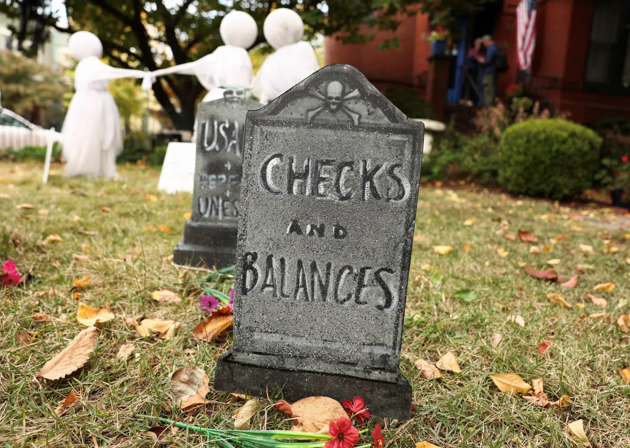 美国民众借墓碑上的碑文暗喻，特朗普上任后，美国三权鼎立互相制衡的政治体制已死。（路透社）