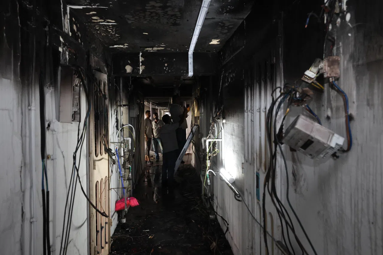 失火组屋外的走廊一片焦黑，电梯中也满是灰烬。工作人员星期六维修损坏的电线。（梁麒麟摄）