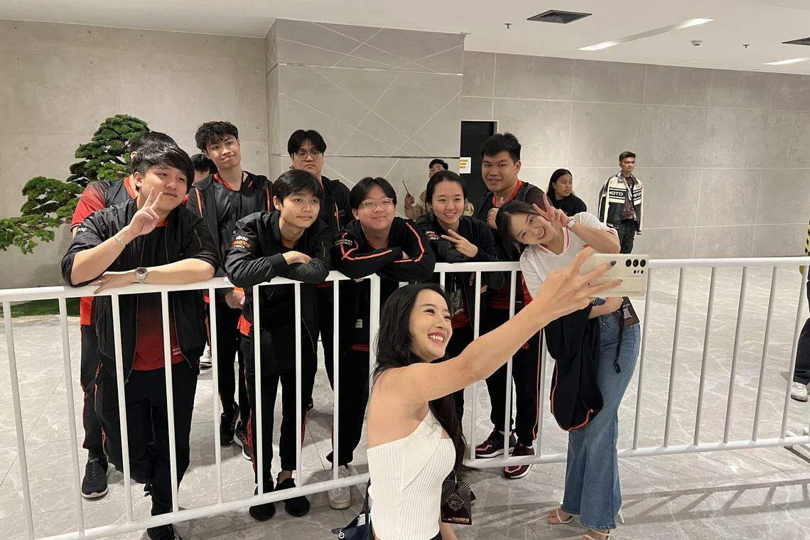 来自新加坡的两位电竞粉丝与我国电竞战队Team Flash合影留念。（薛渤杨摄）