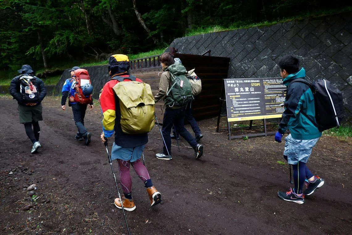 登山客穿过新建的山梨县富士吉田线步道大门入场，这是日本山梨县防止过度旅游所采取的人潮管控措施之一。（路透社）
