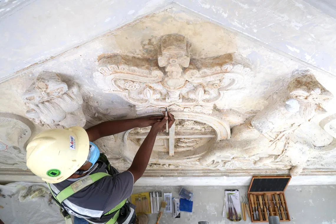 国家博物馆建筑上的皇家徽章和错综复杂的装饰品，已被厚厚的油漆层覆盖。工匠们采用温和的化学试剂，褪去旧漆。（林明顺摄）