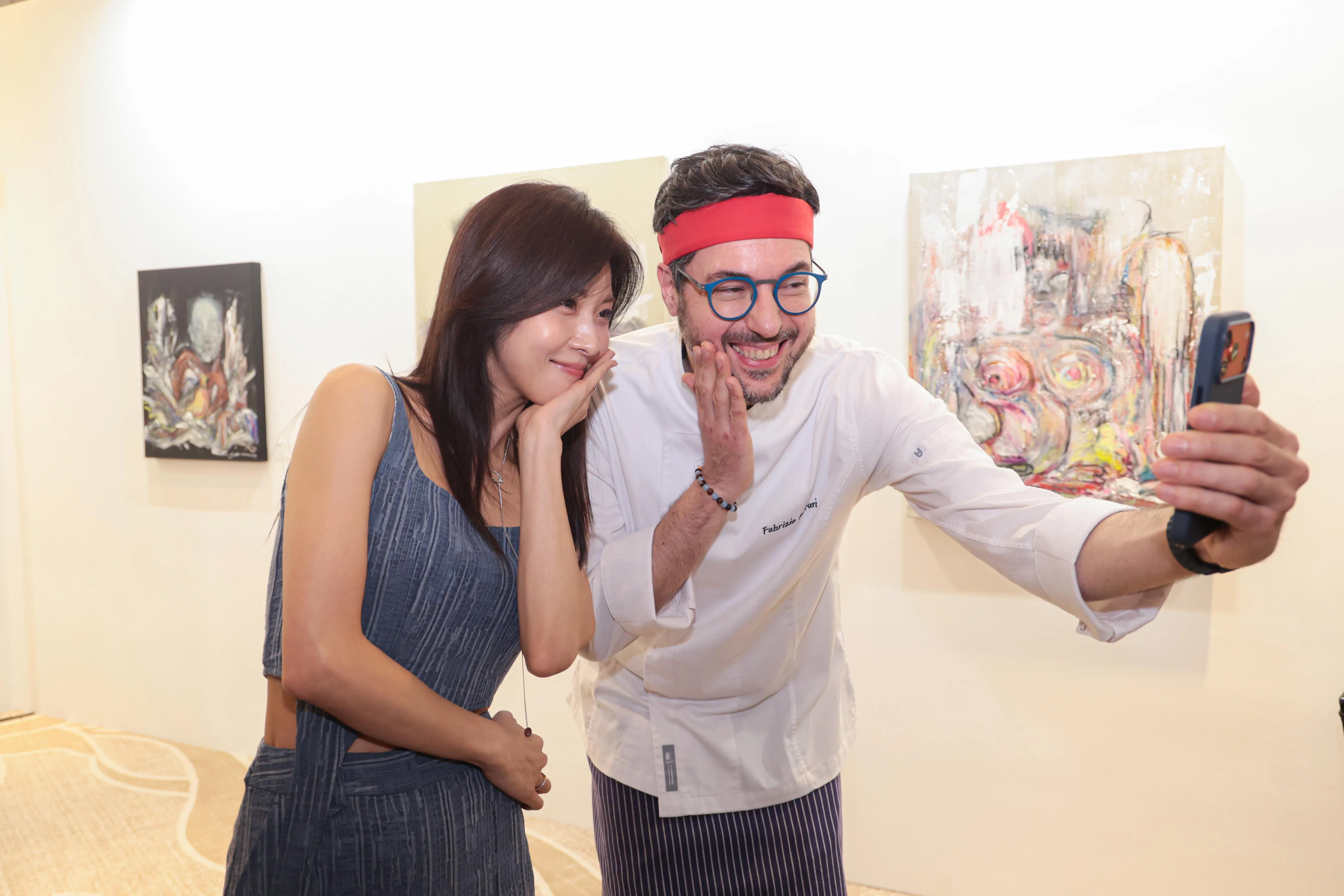 河智苑（左）和第一季《黑白大厨》的Fabrizio Ferrari在她的画作前合影，后者是圣淘沙名胜世界新餐馆的厨师顾问。（李冠卫摄）