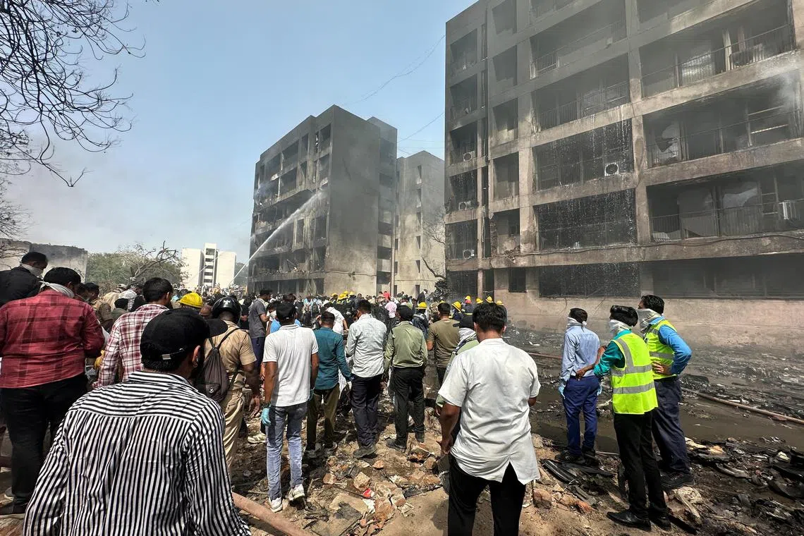 许多人聚集在被客机撞上的大楼附近，消防员正在灭火。（路透社）