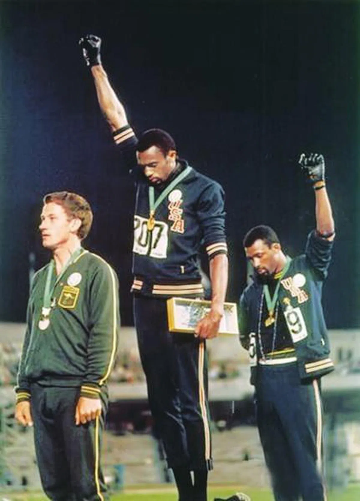 美国非洲裔短跑运动员汤米·史密斯（Tommie Smith）（中）和约翰·卡洛斯（John Carlos）（右）在1968年墨西哥城奥运会颁奖典礼上，举起戴着黑色手套拳头的行为，被认为是奥运史上最公开的政治表达之一。（互联网）