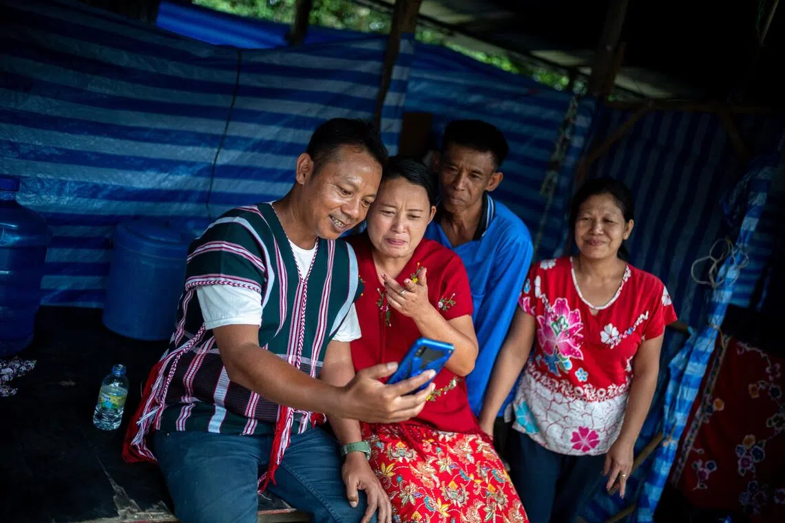 缅甸难民吞敏拉（左起）和妻子离开难民营到龙眼种植园打工，他们年幼的孩子则留在难民营由邻居照顾。夫妻俩想念孩子时，就打视频电话和孩子说话。（路透社）