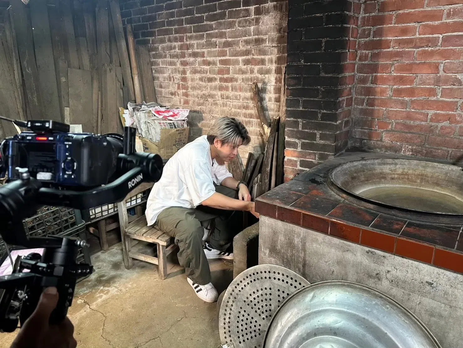 阿弟被委以重任，蹲在厨房里生火。（互联网）