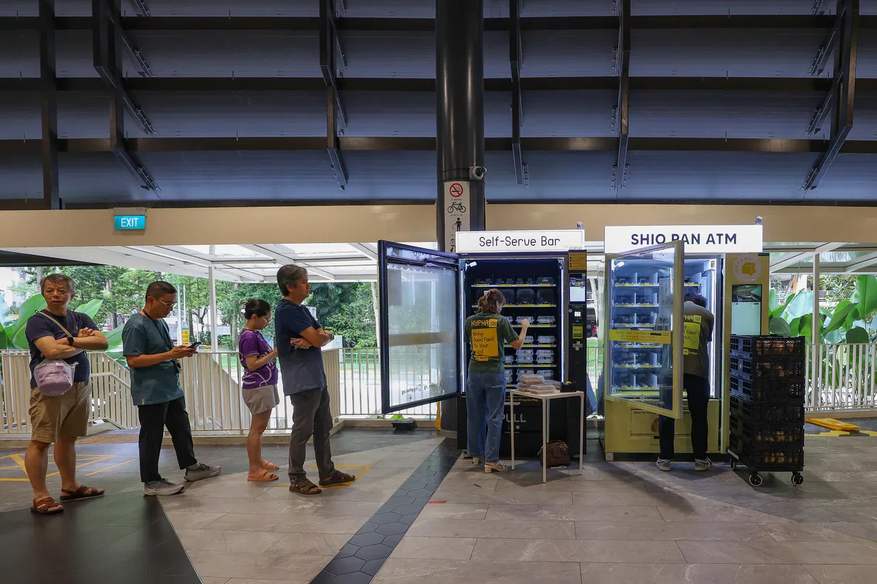 王婉菱和员工为贩卖机补货时已有人开始排队准备购买糕点。（陈心媛摄）