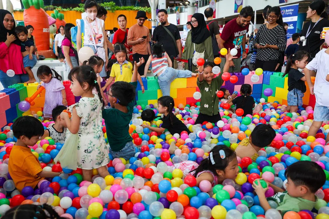 在人协家庭游乐园现场，孩子们在泡泡球池里尽情地玩耍，站在外围的父母也被他们的欢乐所感染。（林明顺摄）