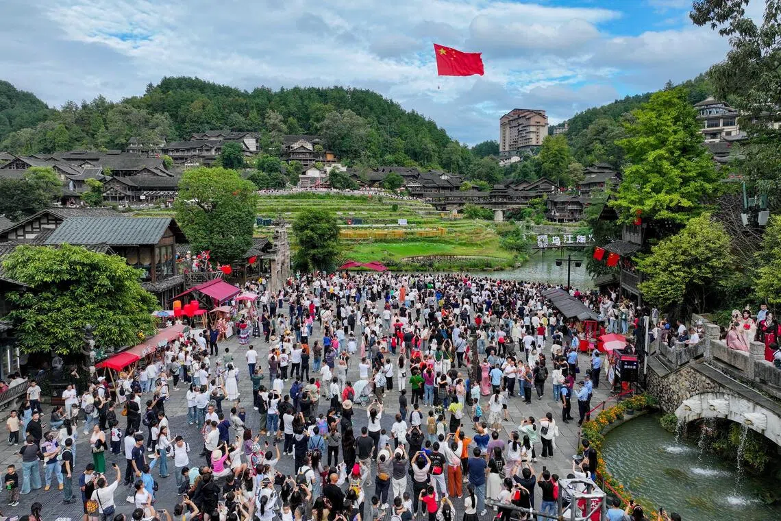 游客星期三（10月1日）在贵州省遵义市乌江寨景区观看“红旗礼献”表演（无人机照片）。（新华社）
