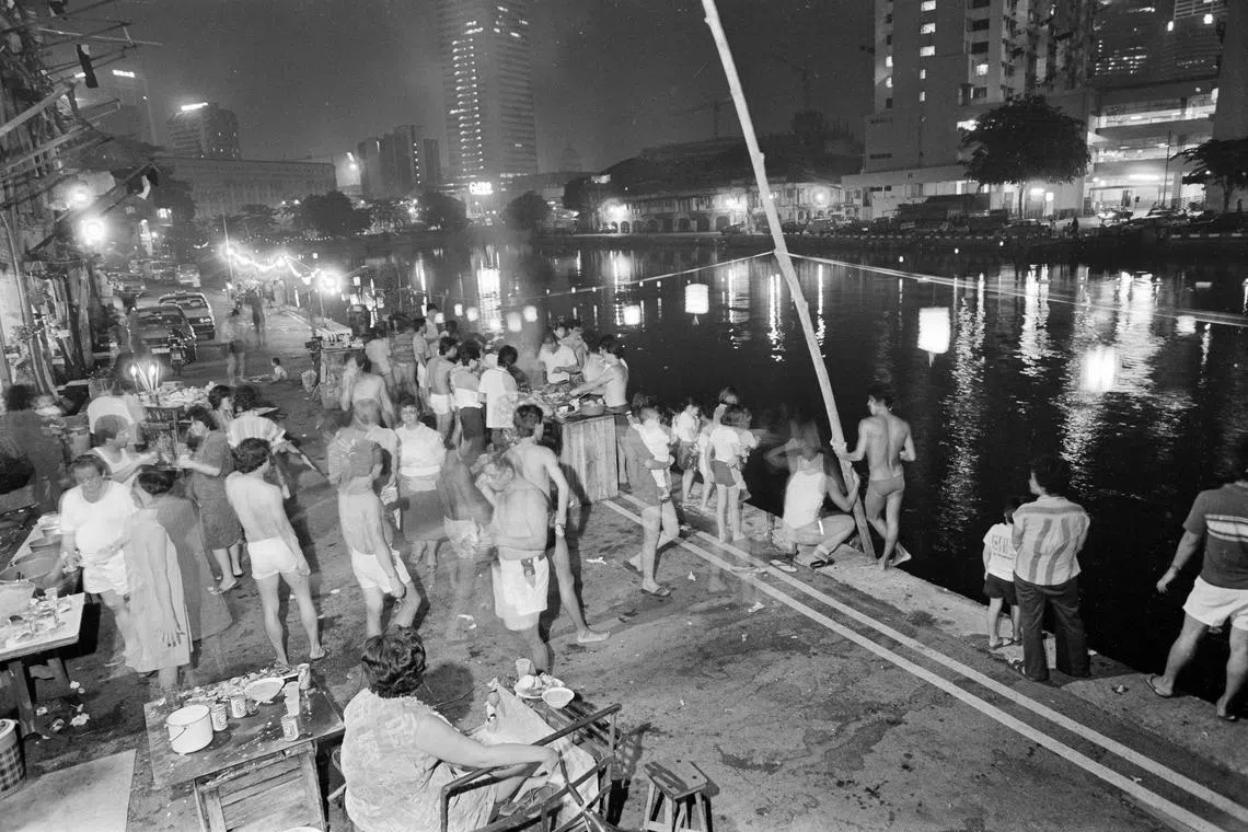1983年中秋夜，新加坡河畔烧烤、拜拜、点灯笼庆祝的人群。环境虽杂，烟火气浓。（档案照）