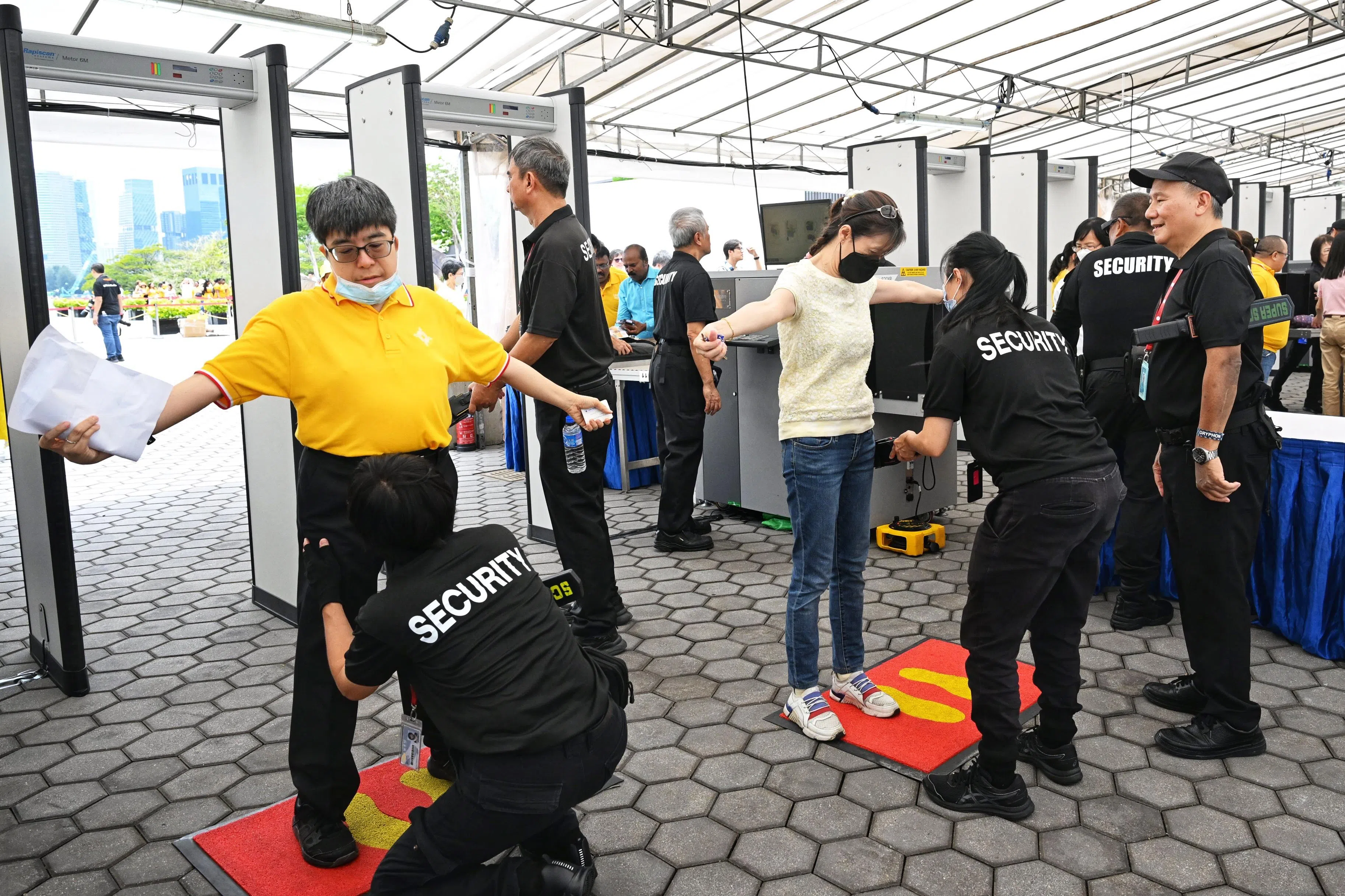 安全检查站中午时分开放，国家体育场外虽排起人龙，但信徒仍有条不紊配合过检。（海峡时报）