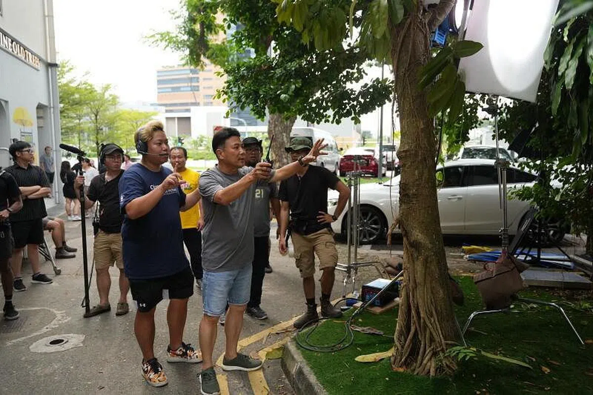 梁志强（前排右）在本地99老树咖啡屋的户外小庭院拍摄贺岁片《猫山王中王》。（谢智扬摄）