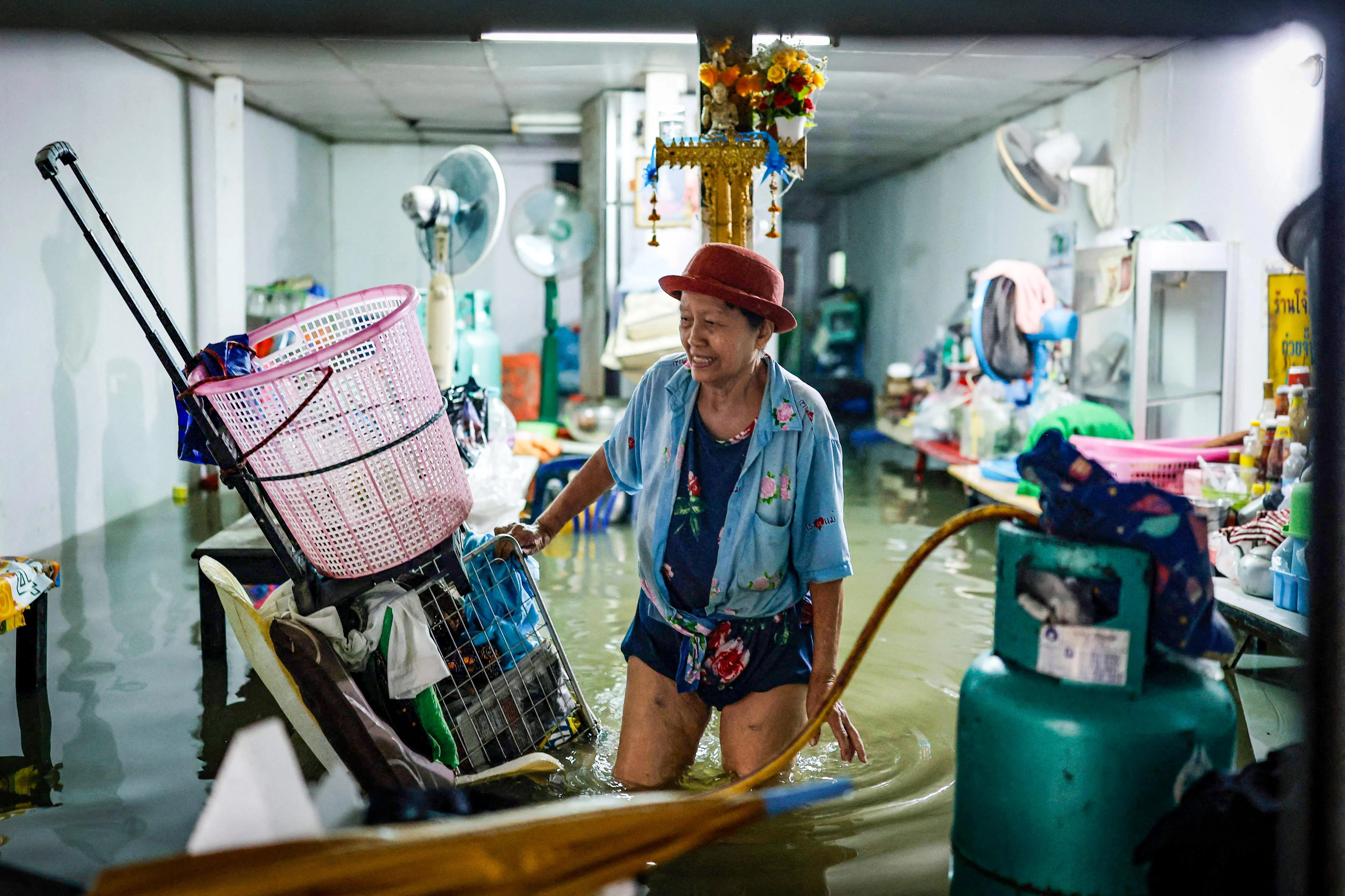 洪水涌入曼谷多个地区的民宅和商店，一名店主在被淹的店内抢救仍可使用的物品。（法新社）