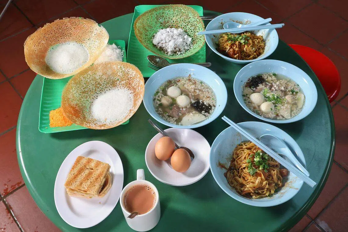 两人一同享用咖椰土司、印度薄煎饼appam和肉脞面等“国民早餐”。（唐家鸿摄）