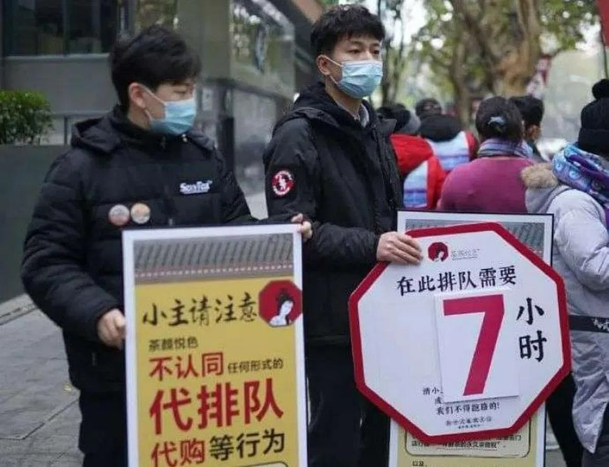茶颜悦色在武汉开业时迎来空前人流，工作人员举着标有排队时间的和“不认同代购”标语的牌子在现场维持秩序。（互联网）