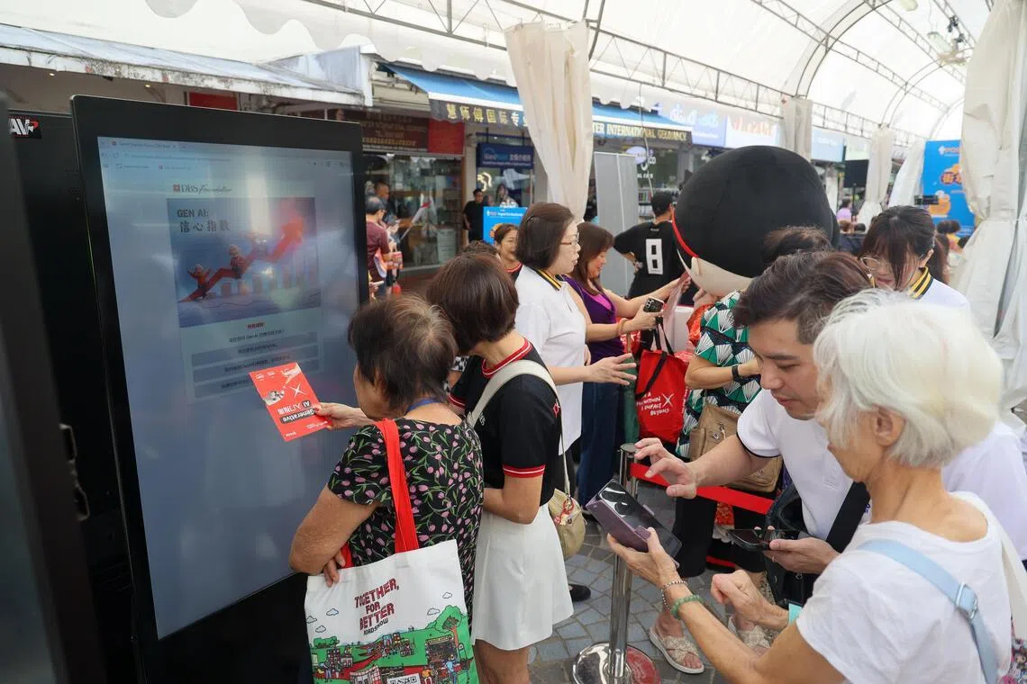星期天举行的“街坊歌台欢乐”活动上，人工智能互动游戏吸引不少公众参与，银行义工在旁向公众细心讲解如何善用AI。（张俊杰摄）