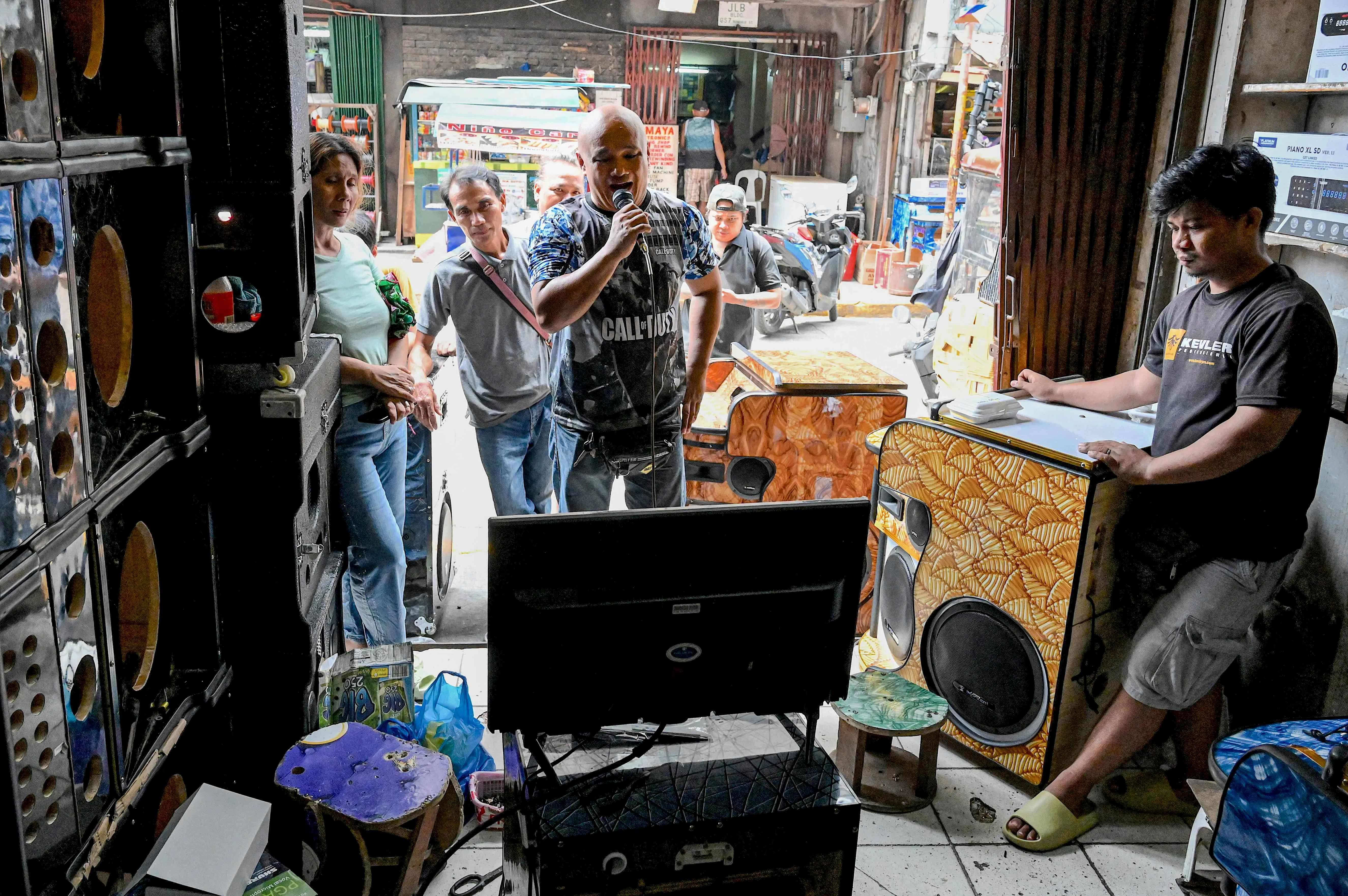 马尼拉奎阿坡区（Quiapo）有许多消费电子产品商店，一名男子在测试店家销售的卡拉OK伴唱机。（法新社）